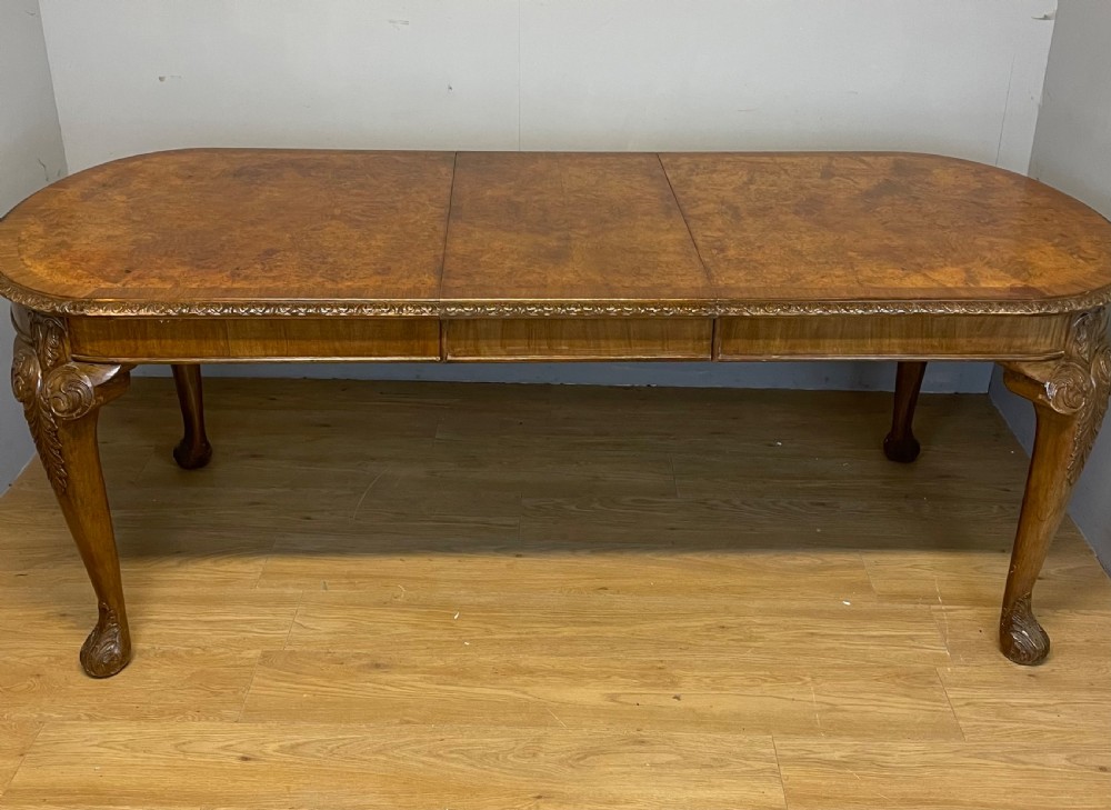 Burr walnut extending dining table on carved cabriole legs 