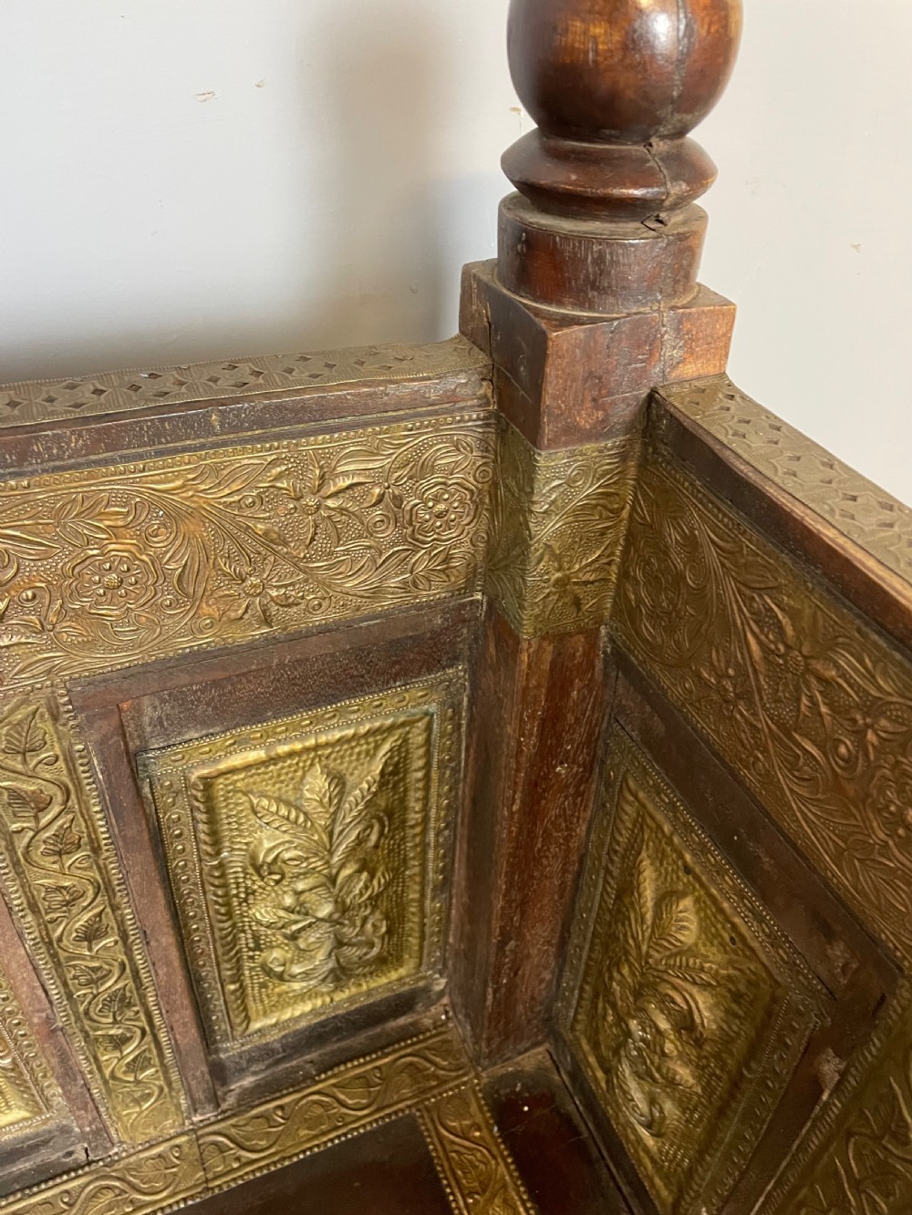 An Anglo Indian dark hardwood box settle featuring embossed brass panels, turned corner finials, and a hinged lift-top seat. View XI