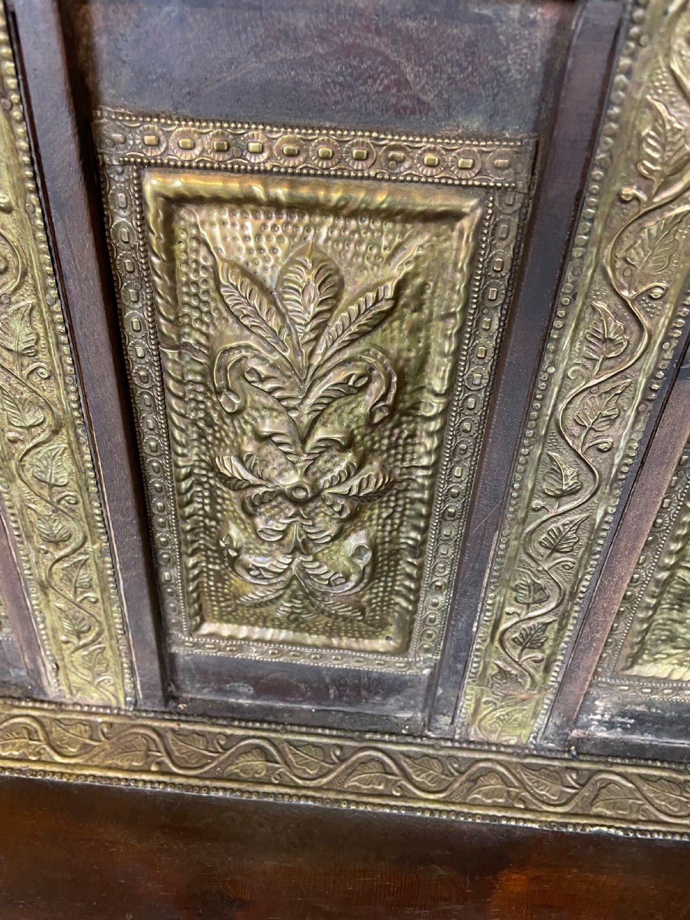 An Anglo Indian dark hardwood box settle featuring embossed brass panels, turned corner finials, and a hinged lift-top seat. View XIV