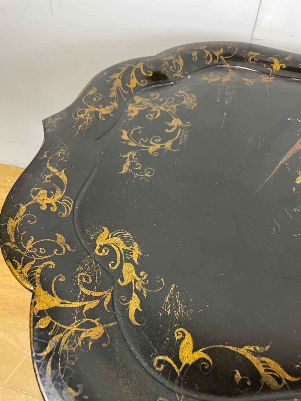 A nineteenth-century black lacquered papier-mache tray with scalloped edges and a central hand-painted floral motif resting on a black iron stand. View VII