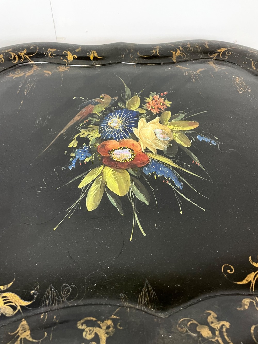 A nineteenth-century black lacquered papier-mache tray with scalloped edges and a central hand-painted floral motif resting on a black iron stand. View VIII