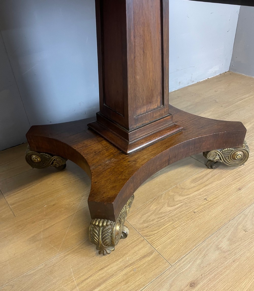 A Regency rosewood drop-leaf sofa table featuring two frieze drawers, a central column, and a quadruped platform base with decorative brass castors. View III