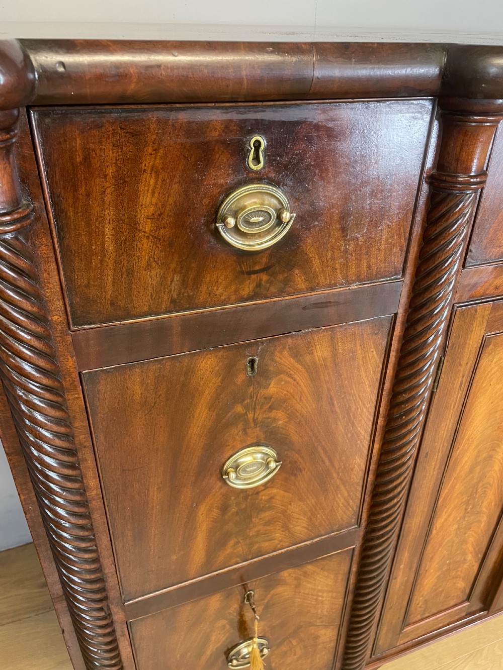 A Regency flame mahogany sideboard featuring rope-twist corner columns, multiple drawers with brass ring handles, and central cupboard doors. View III