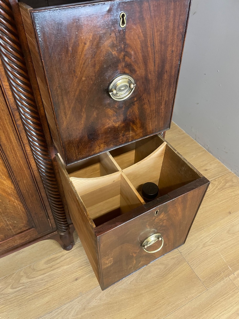 A Regency flame mahogany sideboard featuring rope-twist corner columns, multiple drawers with brass ring handles, and central cupboard doors. View X