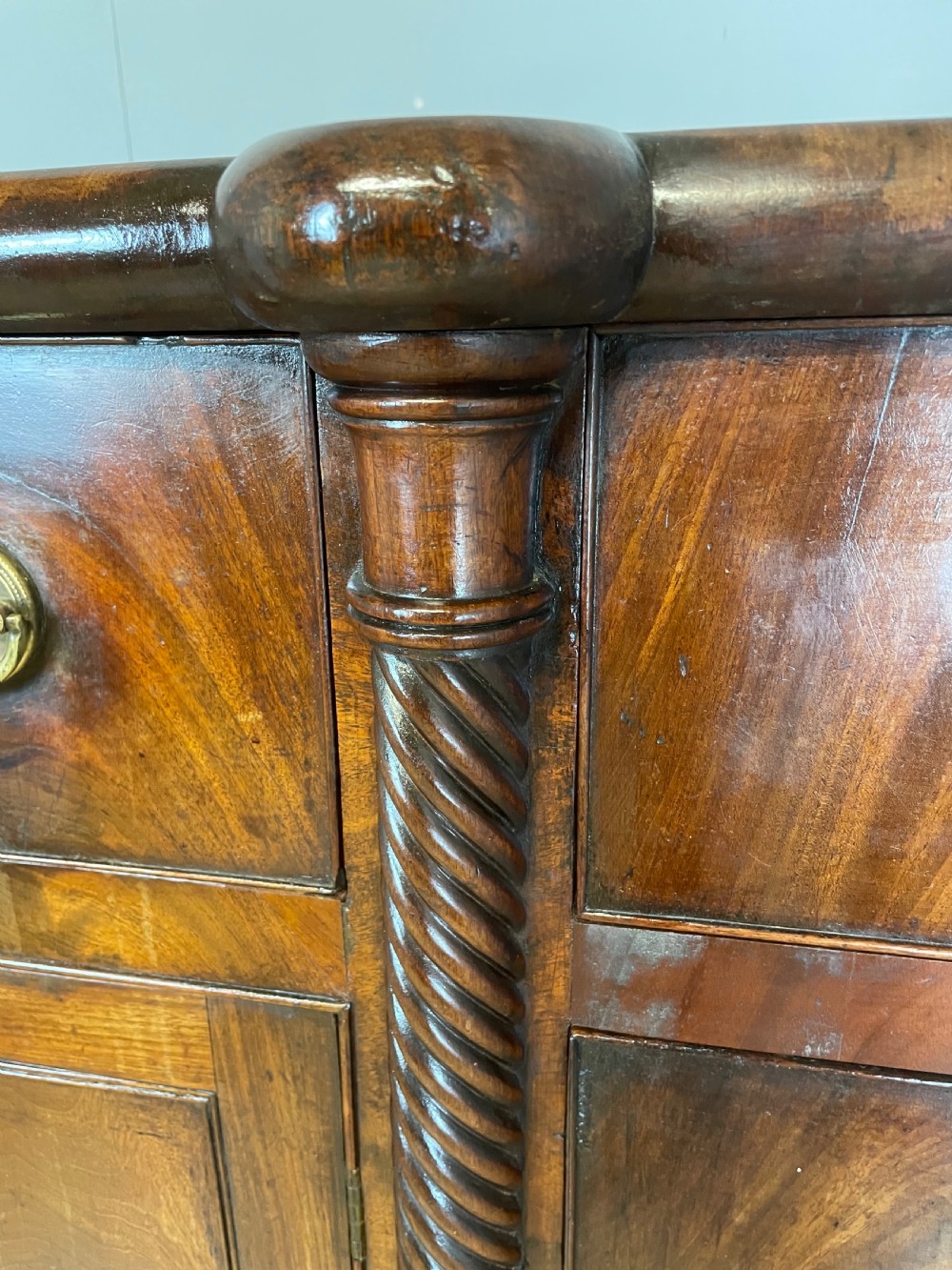 A Regency flame mahogany sideboard featuring rope-twist corner columns, multiple drawers with brass ring handles, and central cupboard doors. View XII