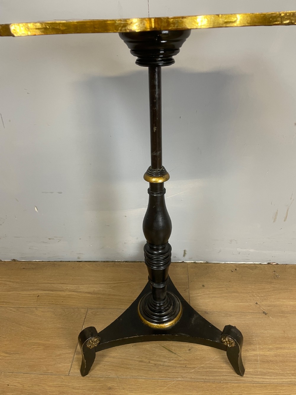 A nineteenth-century Chinoiserie wine table featuring a scalloped black lacquered top with gilded oriental landscape decoration, supported by a turned ebonised column on a tripartite base. View IV