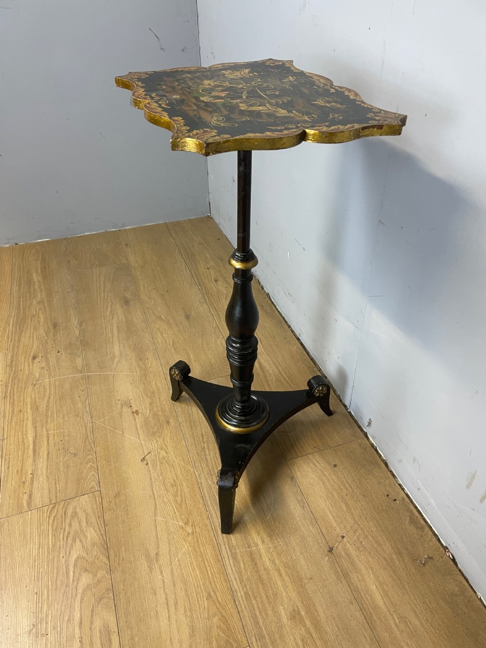 A nineteenth-century Chinoiserie wine table featuring a scalloped black lacquered top with gilded oriental landscape decoration, supported by a turned ebonised column on a tripartite base. View VII