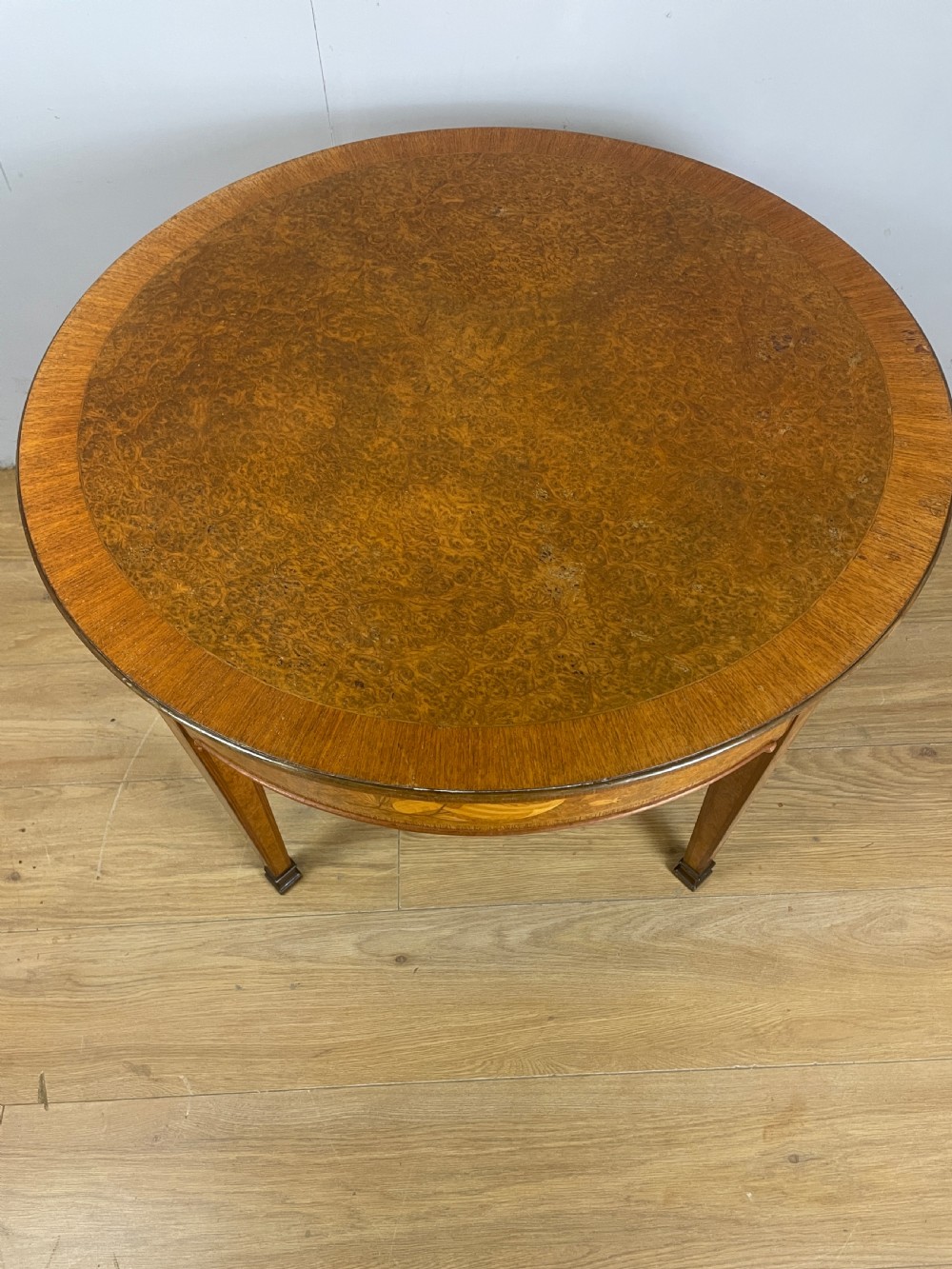 A circular 1930s burr walnut coffee table featuring floral marquetry on the apron and square tapered legs. View III