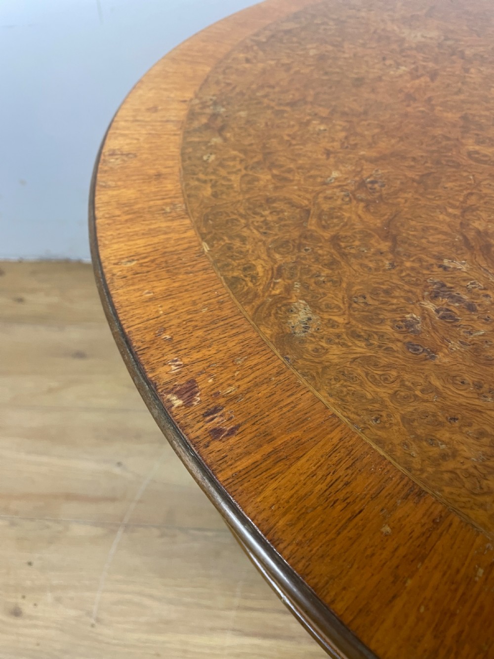A circular 1930s burr walnut coffee table featuring floral marquetry on the apron and square tapered legs. View VII