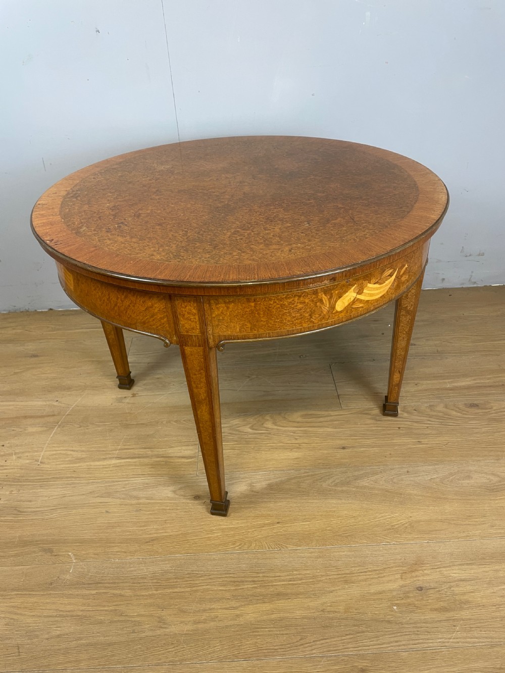 A circular 1930s burr walnut coffee table featuring floral marquetry on the apron and square tapered legs. View VIII