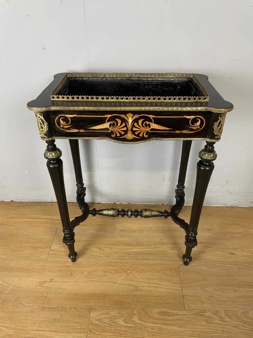 A 19th-century ebonised rectangular jardiniere table featuring intricate marquetry inlay, gilt-bronze mounts, turned legs, and a pierced brass gallery.
