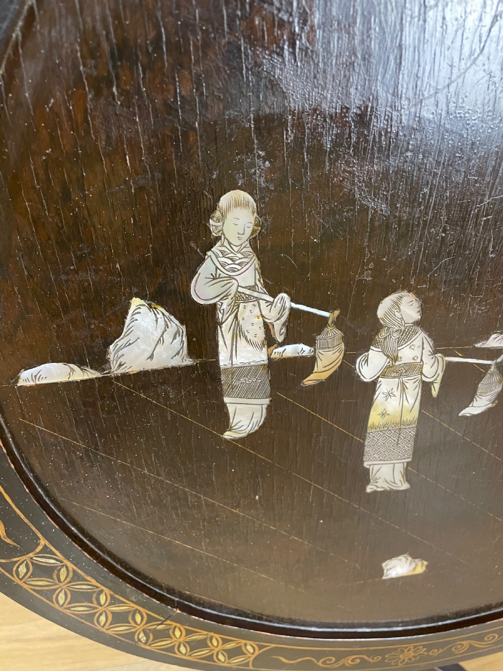 An Edwardian black lacquered circular tripod table decorated with mother-of-pearl figurative inlays and gilt floral borders. View III