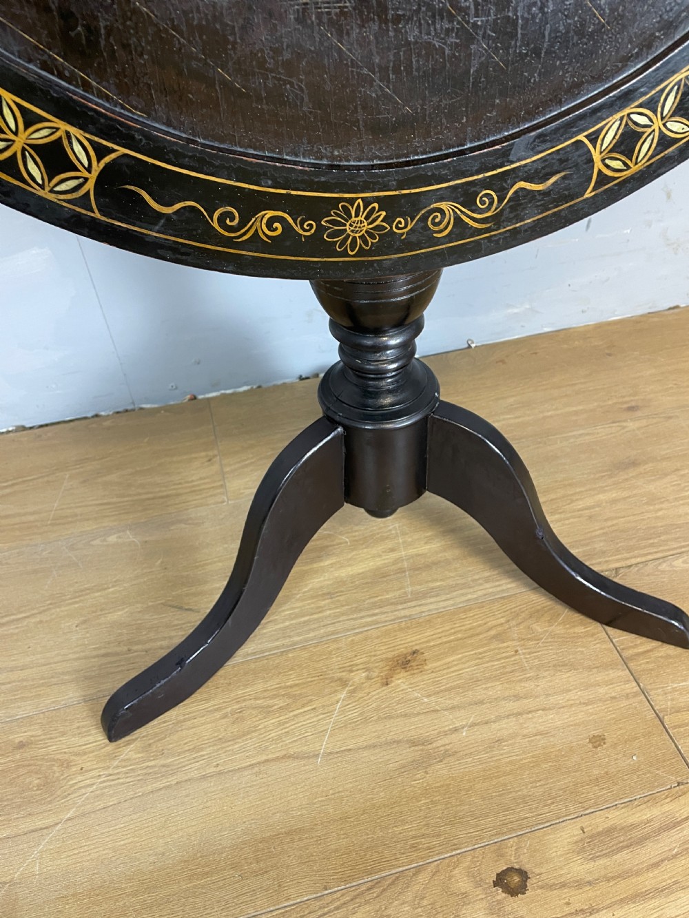 An Edwardian black lacquered circular tripod table decorated with mother-of-pearl figurative inlays and gilt floral borders. View IV
