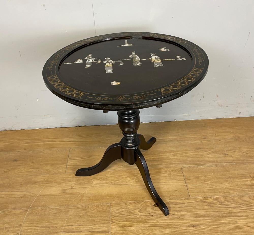 An Edwardian black lacquered circular tripod table decorated with mother-of-pearl figurative inlays and gilt floral borders. View VIII