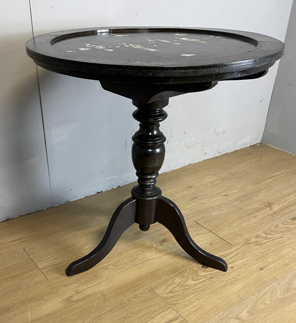 An Edwardian black lacquered circular tripod table decorated with mother-of-pearl figurative inlays and gilt floral borders. View IX