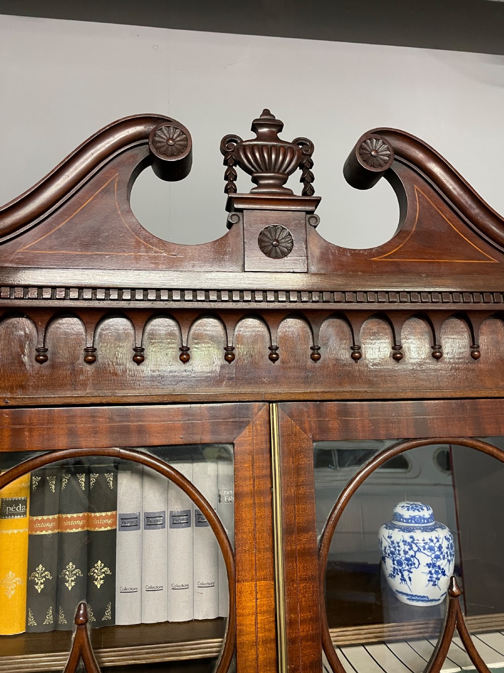 An Edwardian mahogany breakfront library bookcase with astragal glazed doors, a swan-neck pediment, and inlaid wood cabinet doors. View III