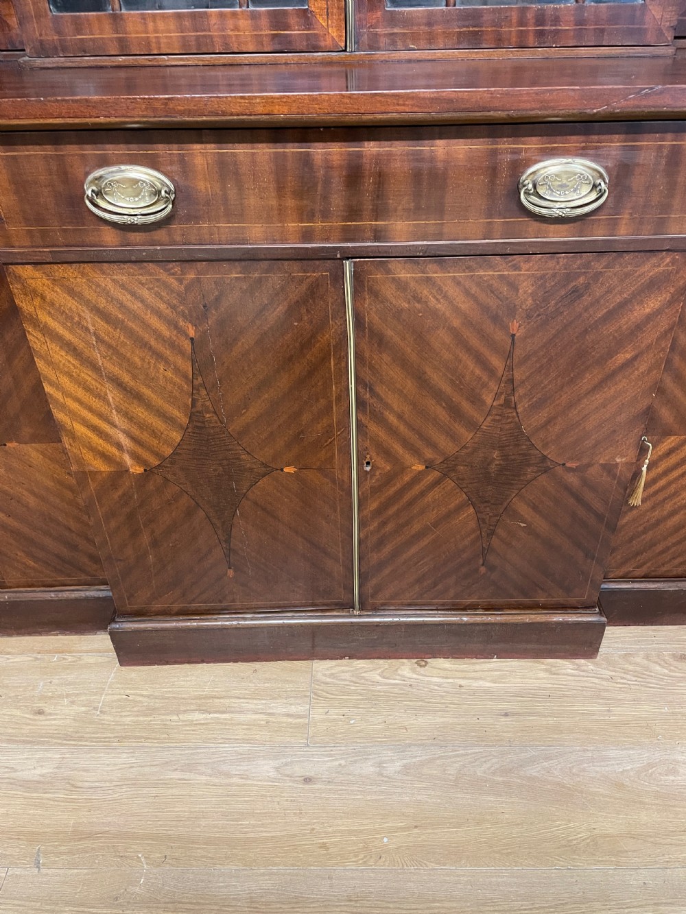 An Edwardian mahogany breakfront library bookcase with astragal glazed doors, a swan-neck pediment, and inlaid wood cabinet doors. View VI