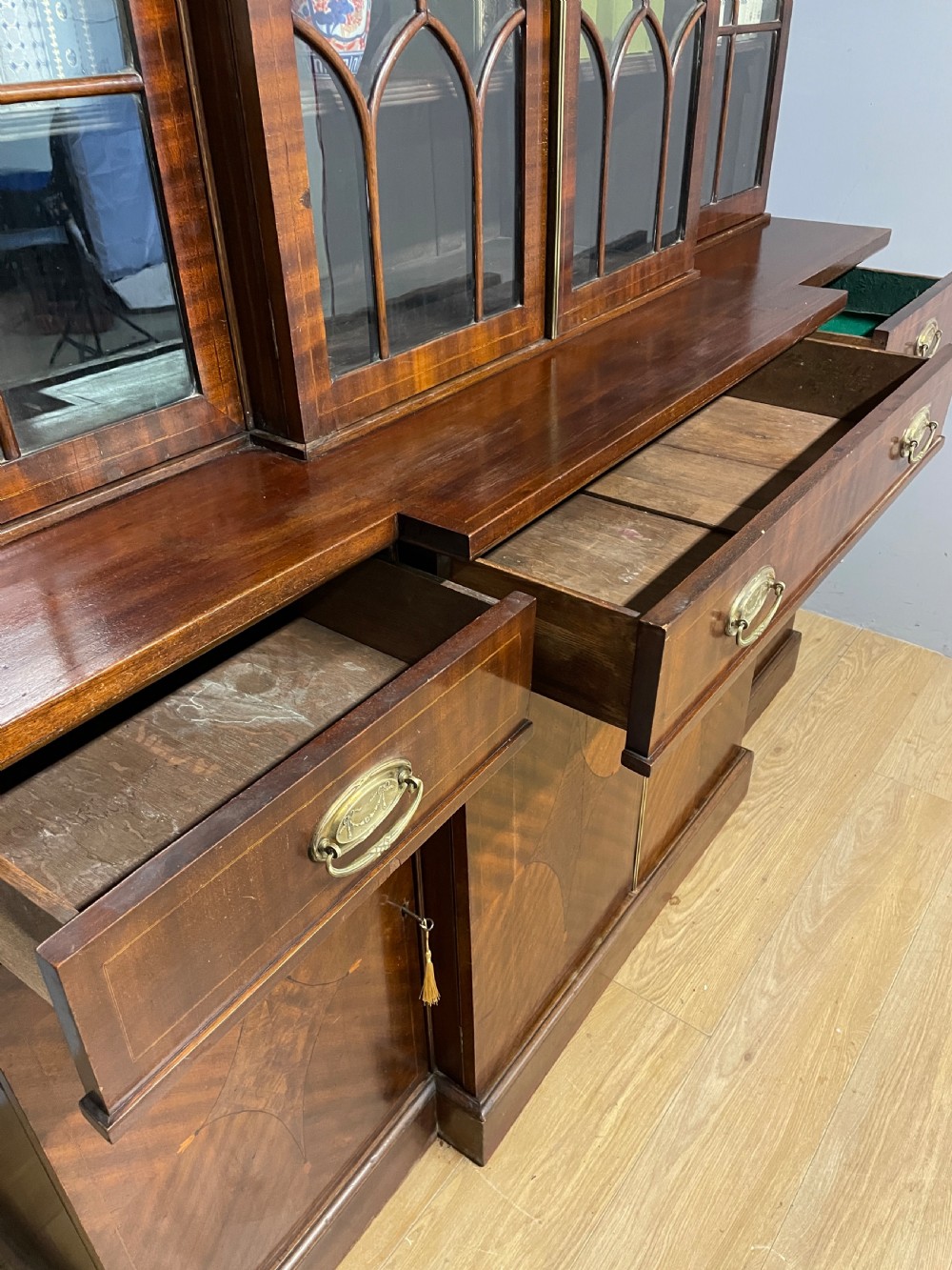 An Edwardian mahogany breakfront library bookcase with astragal glazed doors, a swan-neck pediment, and inlaid wood cabinet doors. View VII
