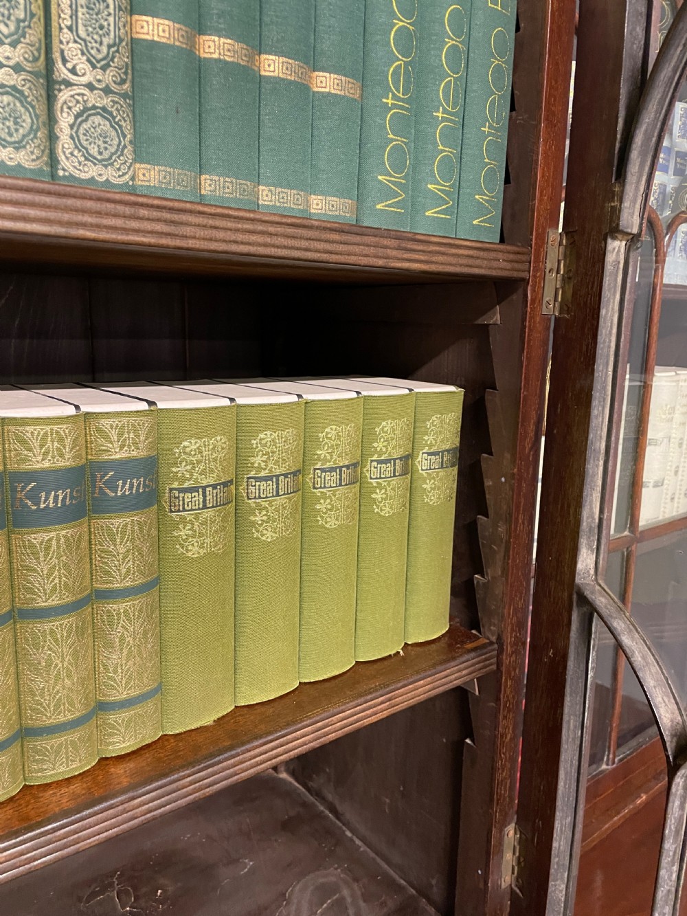 An Edwardian mahogany breakfront library bookcase with astragal glazed doors, a swan-neck pediment, and inlaid wood cabinet doors. View X