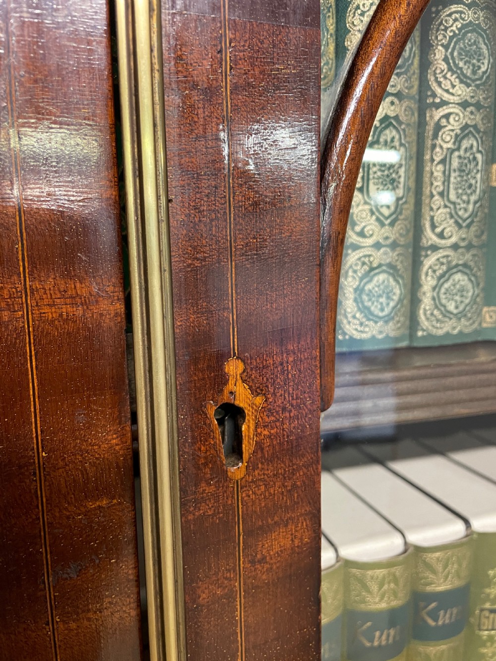 An Edwardian mahogany breakfront library bookcase with astragal glazed doors, a swan-neck pediment, and inlaid wood cabinet doors. View XI