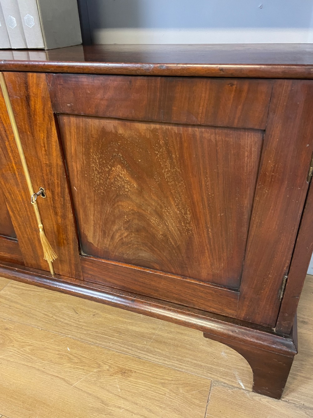 A 19th-century flame mahogany waterfall freestanding bookcase featuring graduated open shelves above a two-door lower cupboard with bracket feet. View III