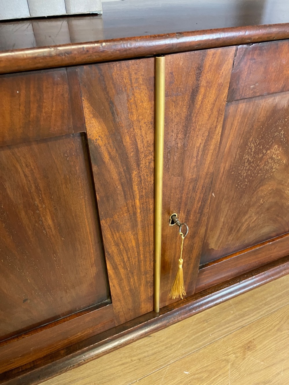 A 19th-century flame mahogany waterfall freestanding bookcase featuring graduated open shelves above a two-door lower cupboard with bracket feet. View V