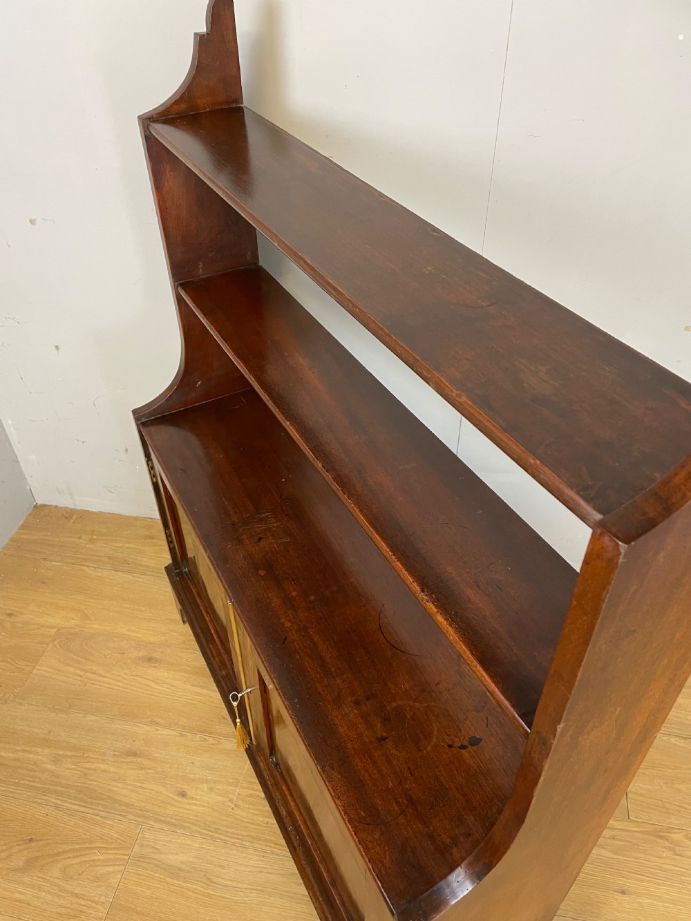 A 19th-century flame mahogany waterfall freestanding bookcase featuring graduated open shelves above a two-door lower cupboard with bracket feet. View X