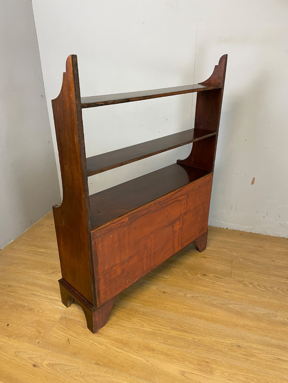 A 19th-century flame mahogany waterfall freestanding bookcase featuring graduated open shelves above a two-door lower cupboard with bracket feet. View XI
