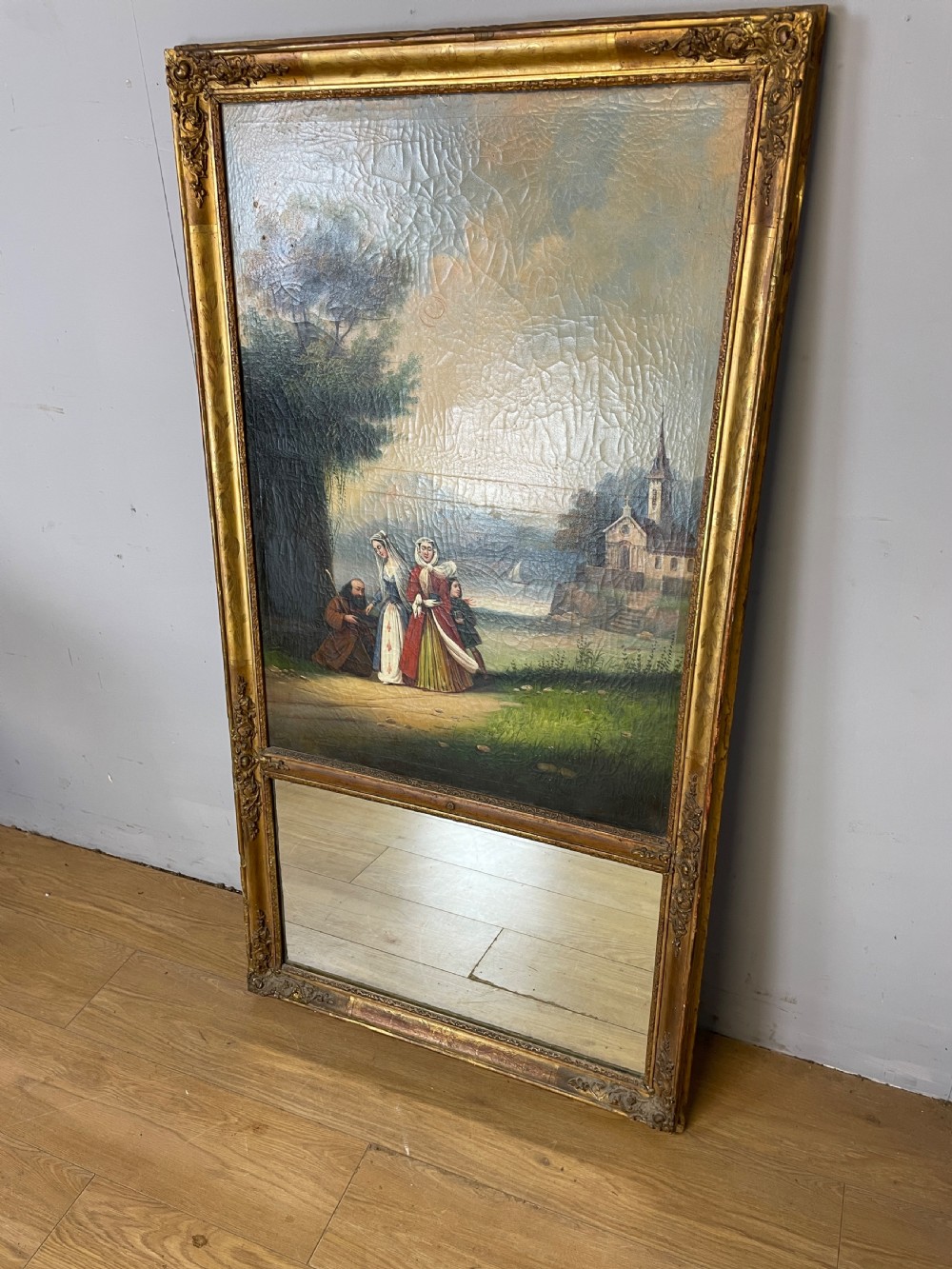 A tall 19th-century gilt-framed pier mirror featuring an upper integral landscape oil painting above a rectangular reflective mirror panel.