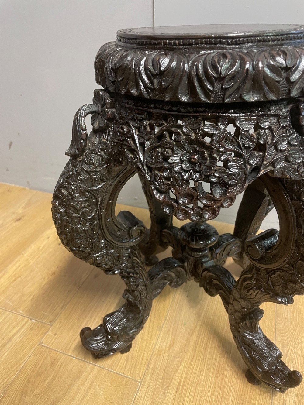 A dark circular carved hardwood stand with pierced foliate aprons and heavy curved legs with detailed carved feet. View IV