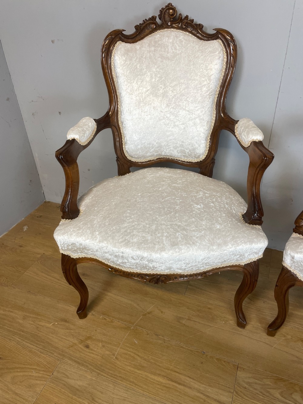 A pair of French carved walnut open armchairs upholstered in cream crushed fabric with cabriole legs and ornate cresting. View IV