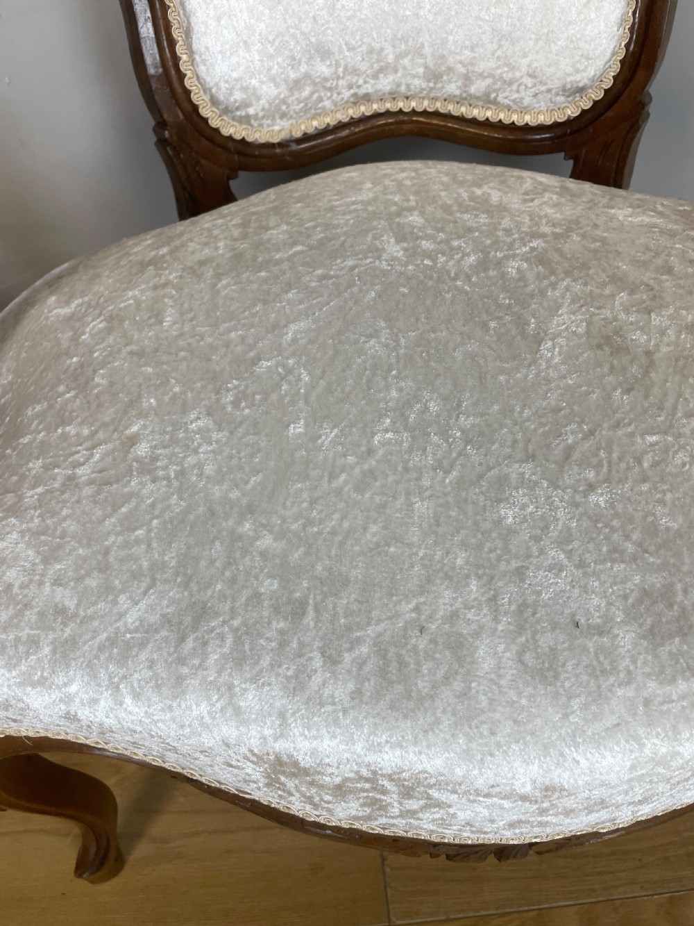 A pair of French carved walnut open armchairs upholstered in cream crushed fabric with cabriole legs and ornate cresting. View IX