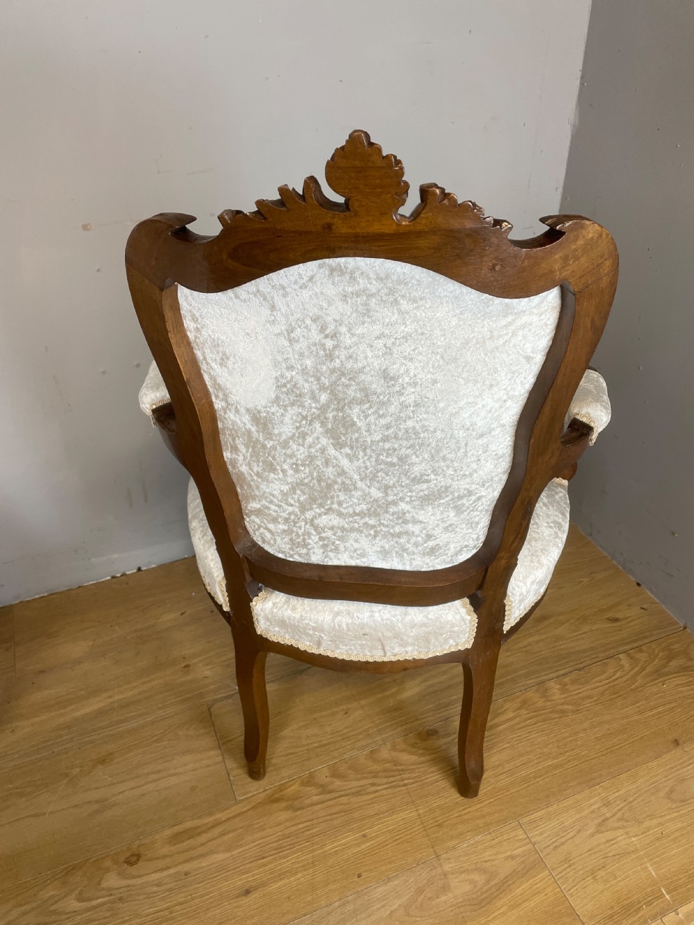 A pair of French carved walnut open armchairs upholstered in cream crushed fabric with cabriole legs and ornate cresting. View X