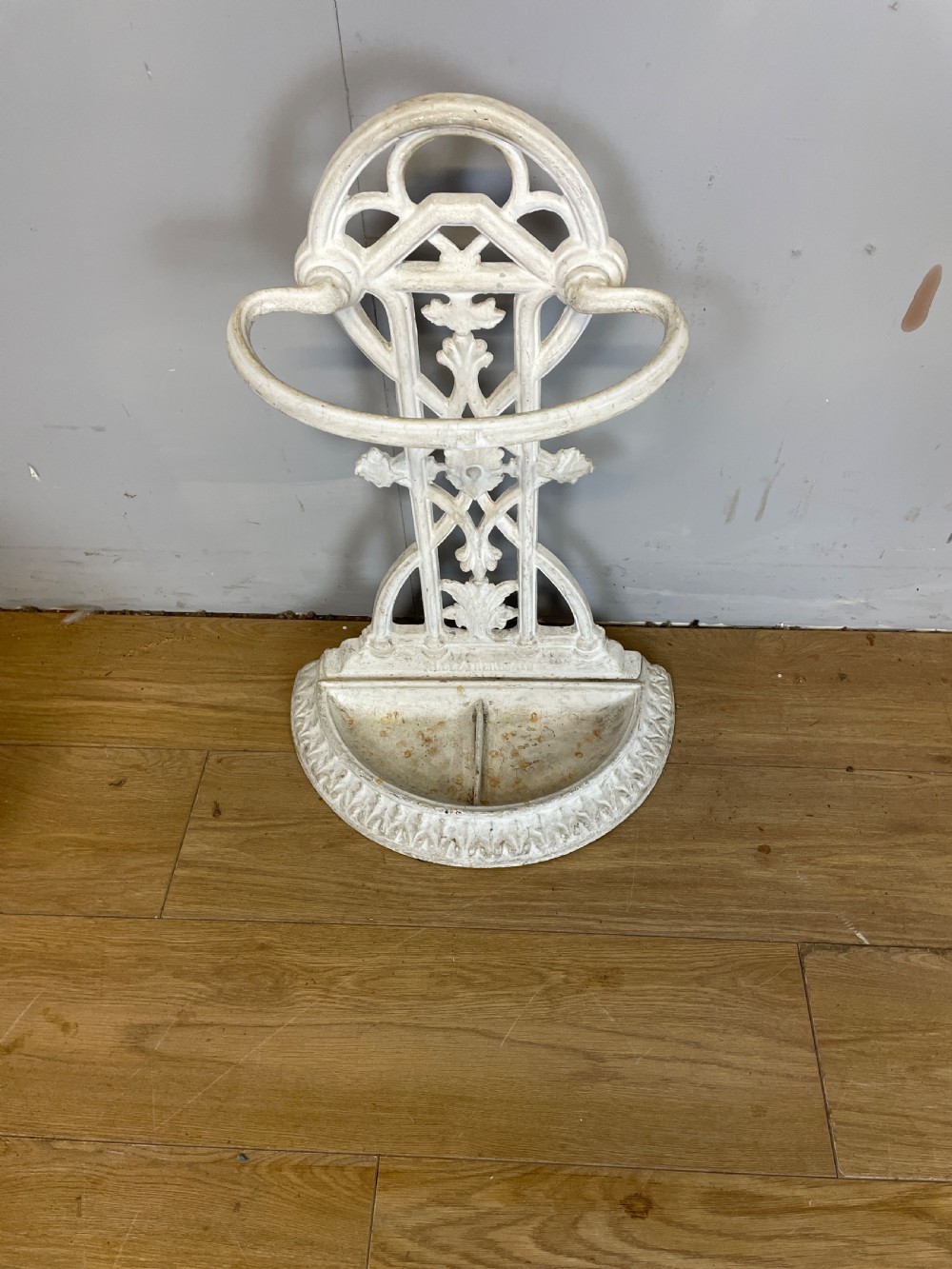 A white painted 19th-century Victorian cast iron stick stand featuring intricate Gothic tracery, an upper retaining hoop, and a divided drip tray base. View II
