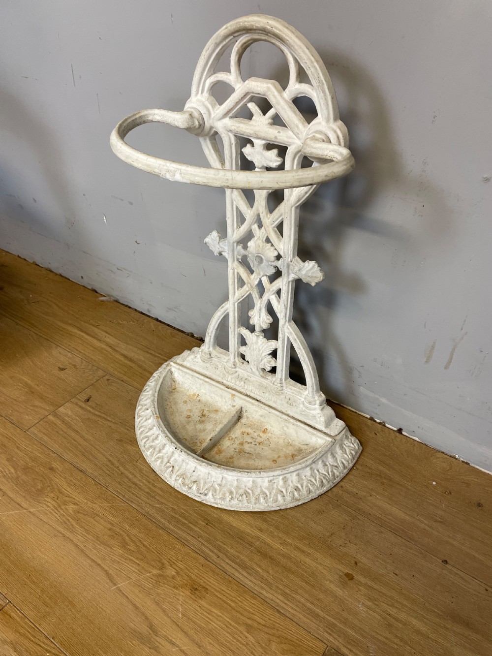 A white painted 19th-century Victorian cast iron stick stand featuring intricate Gothic tracery, an upper retaining hoop, and a divided drip tray base. View III