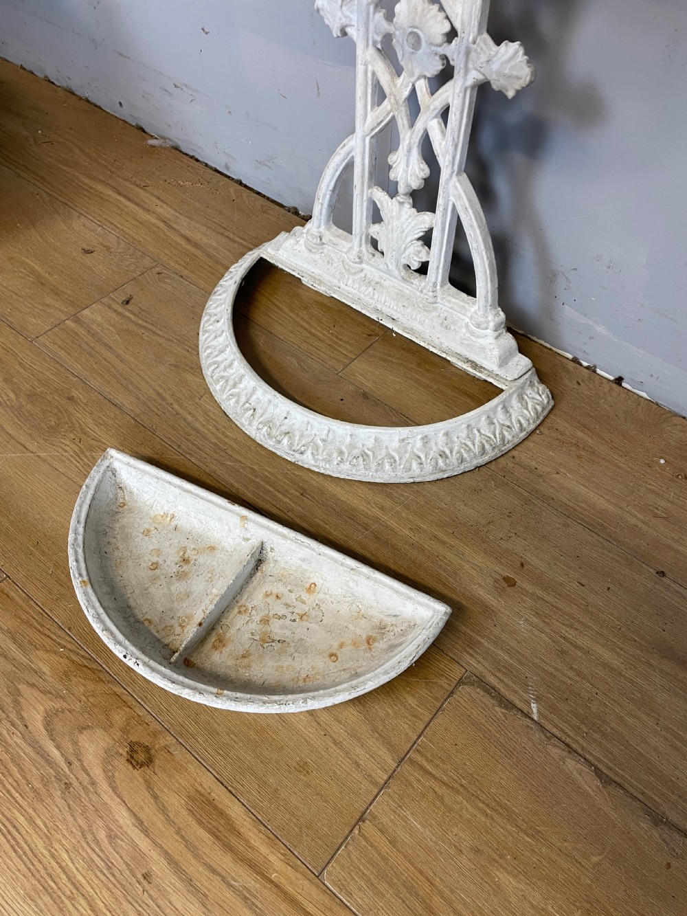 A white painted 19th-century Victorian cast iron stick stand featuring intricate Gothic tracery, an upper retaining hoop, and a divided drip tray base. View VII