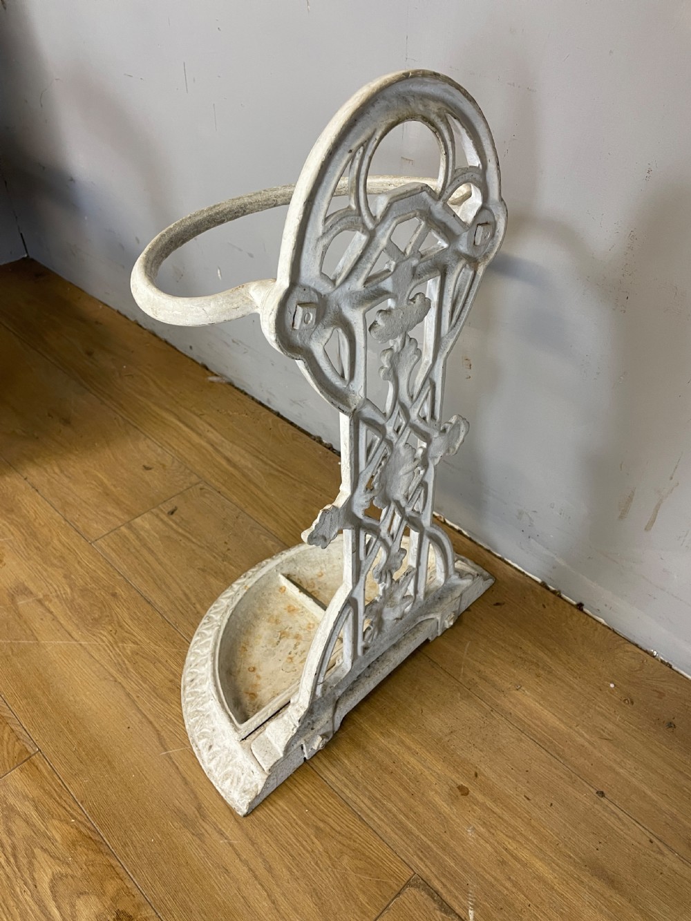 A white painted 19th-century Victorian cast iron stick stand featuring intricate Gothic tracery, an upper retaining hoop, and a divided drip tray base. View VIII