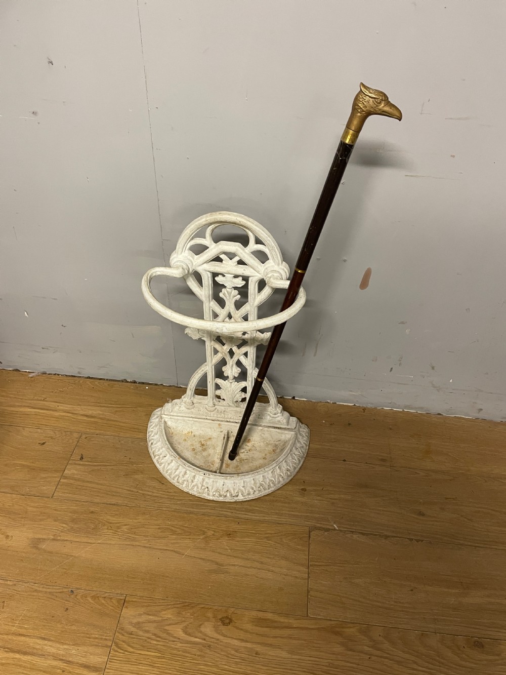 A white painted 19th-century Victorian cast iron stick stand featuring intricate Gothic tracery, an upper retaining hoop, and a divided drip tray base. View IX