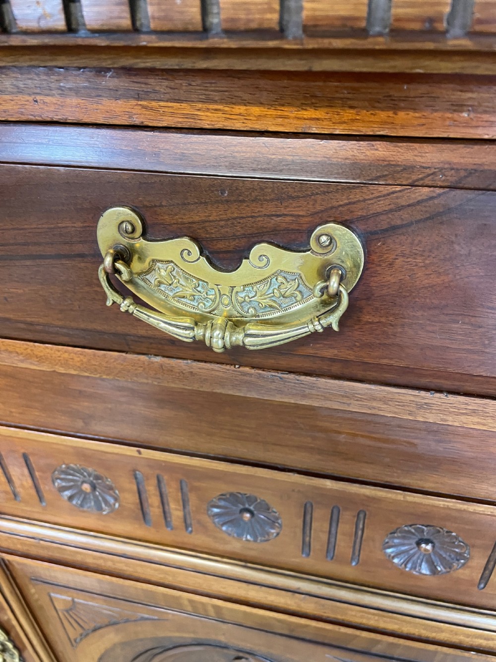 A late 19th-century solid walnut Arts and Crafts bookcase over cupboard featuring upper geometric astragal glazed doors and lower carved foliate panels. View VII