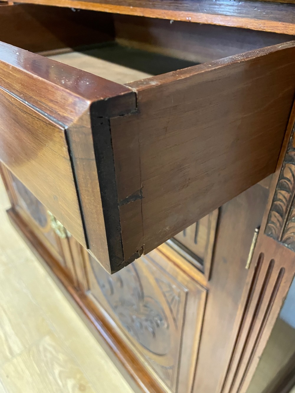 A late 19th-century solid walnut Arts and Crafts bookcase over cupboard featuring upper geometric astragal glazed doors and lower carved foliate panels. View IX