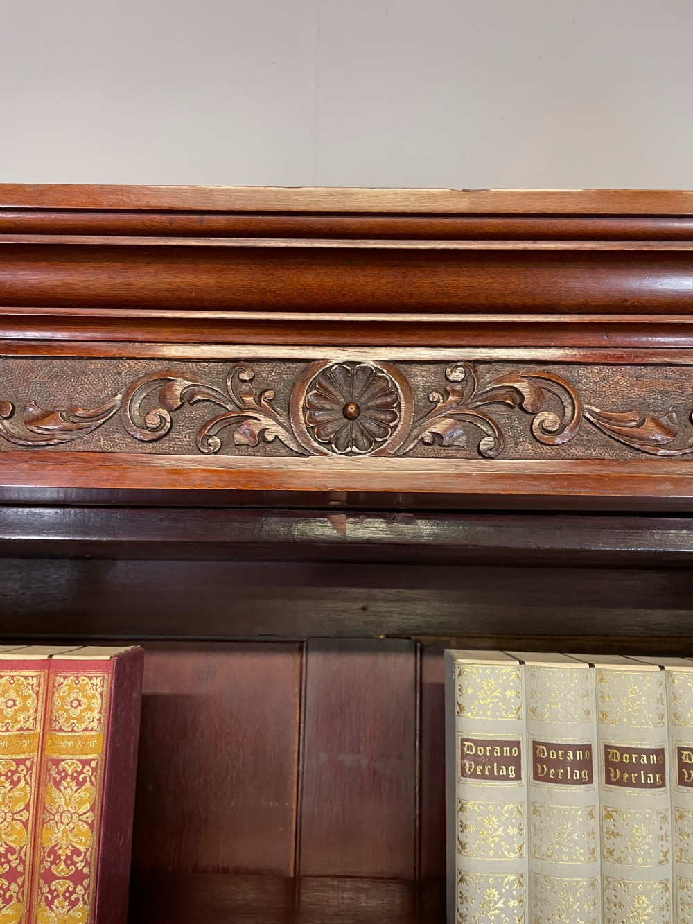 A late 19th-century solid walnut Arts and Crafts bookcase over cupboard featuring upper geometric astragal glazed doors and lower carved foliate panels. View XII