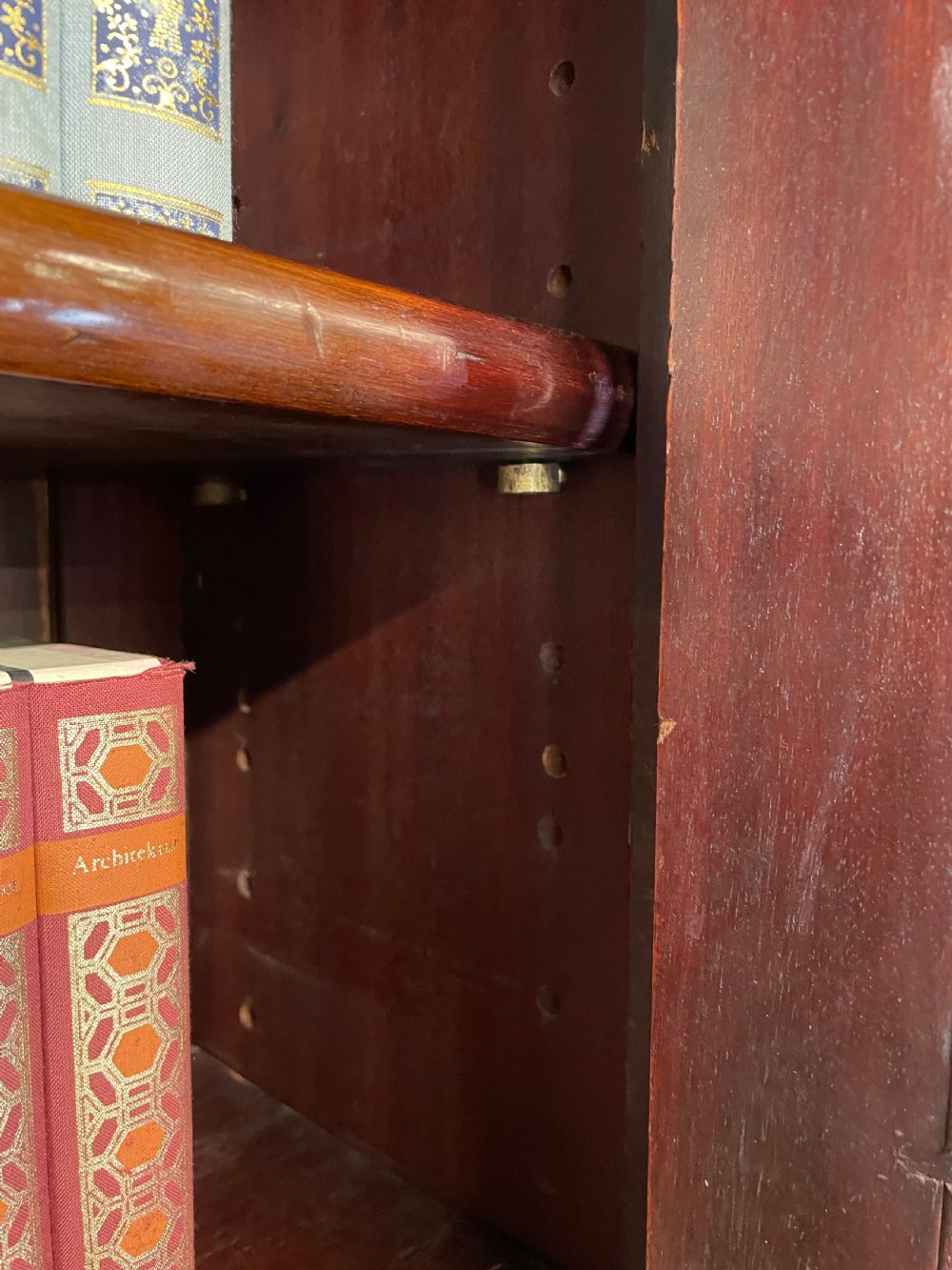 A late 19th-century solid walnut Arts and Crafts bookcase over cupboard featuring upper geometric astragal glazed doors and lower carved foliate panels. View XIV