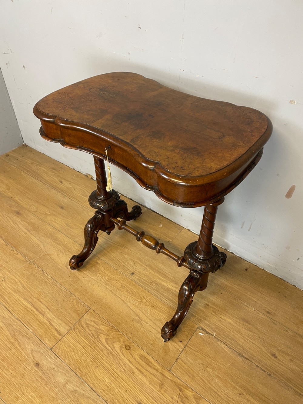 A Victorian burr walnut work table shown with its hinged lid open, revealing intricate fretwork covers, internal compartments, and carved turned legs. View II