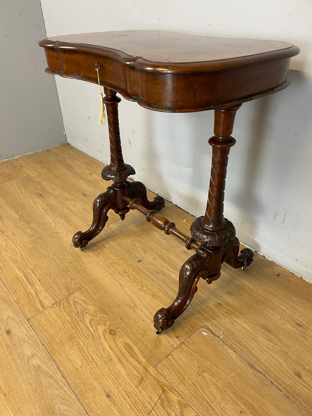 A Victorian burr walnut work table shown with its hinged lid open, revealing intricate fretwork covers, internal compartments, and carved turned legs. View IV