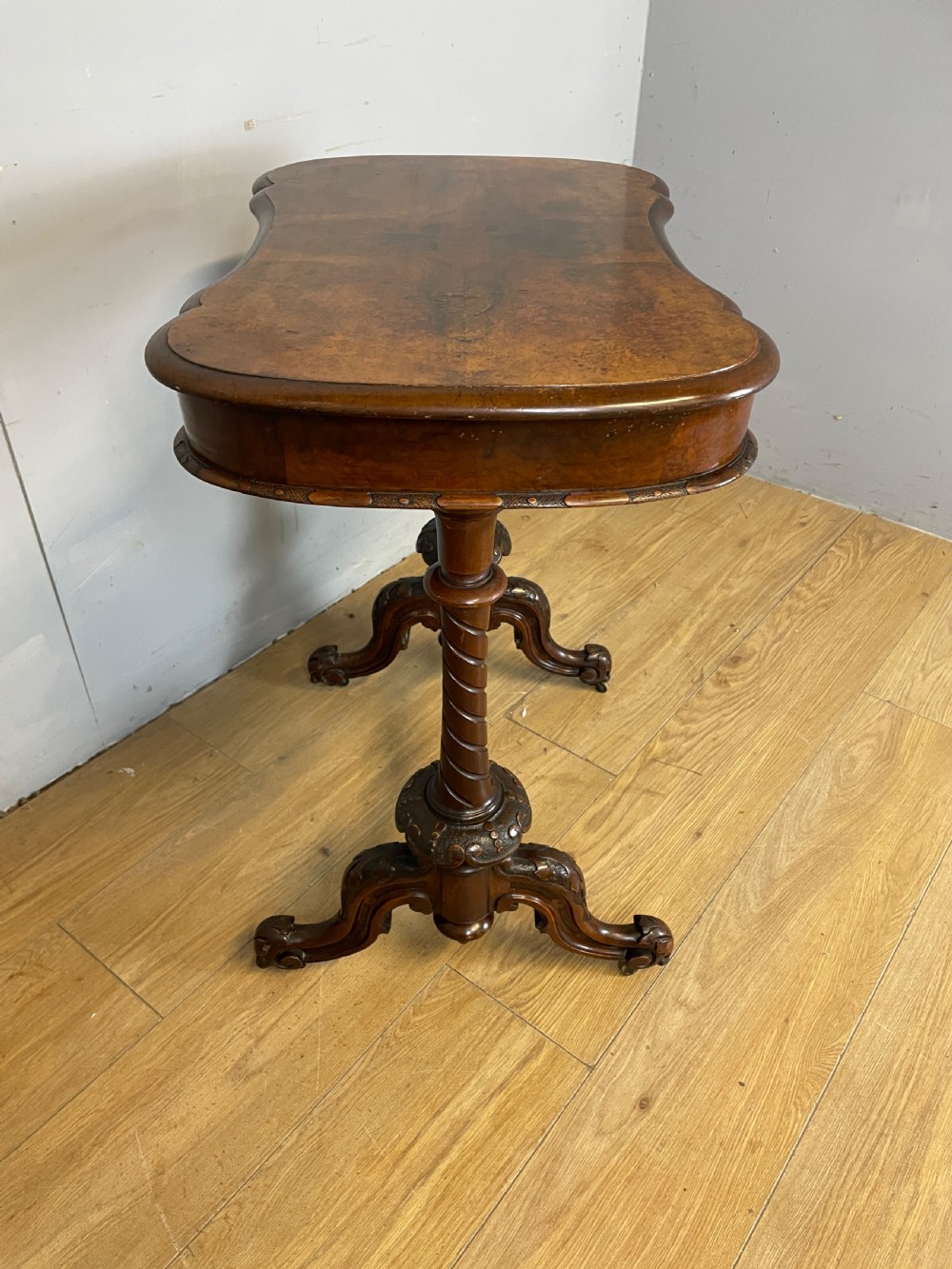 A Victorian burr walnut work table shown with its hinged lid open, revealing intricate fretwork covers, internal compartments, and carved turned legs. View VII