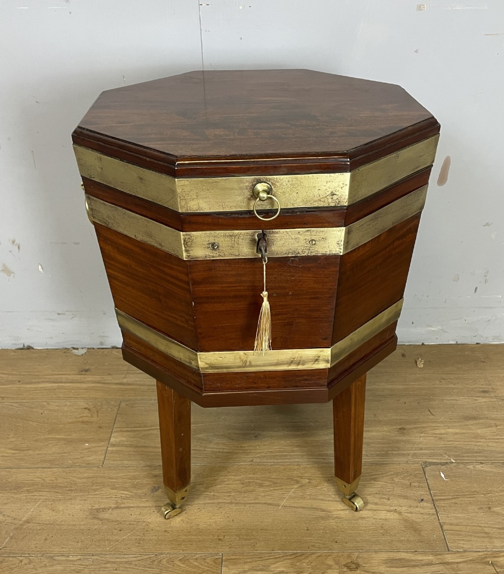 An octagonal Georgian mahogany cellarette bound with brass bands and supported by four square tapered legs on brass castors.