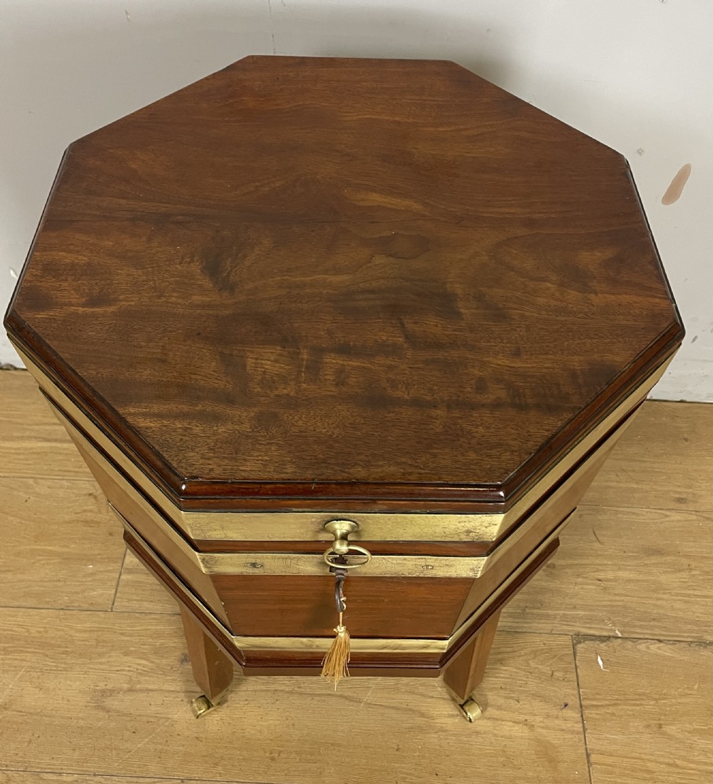 An octagonal Georgian mahogany cellarette bound with brass bands and supported by four square tapered legs on brass castors. View III