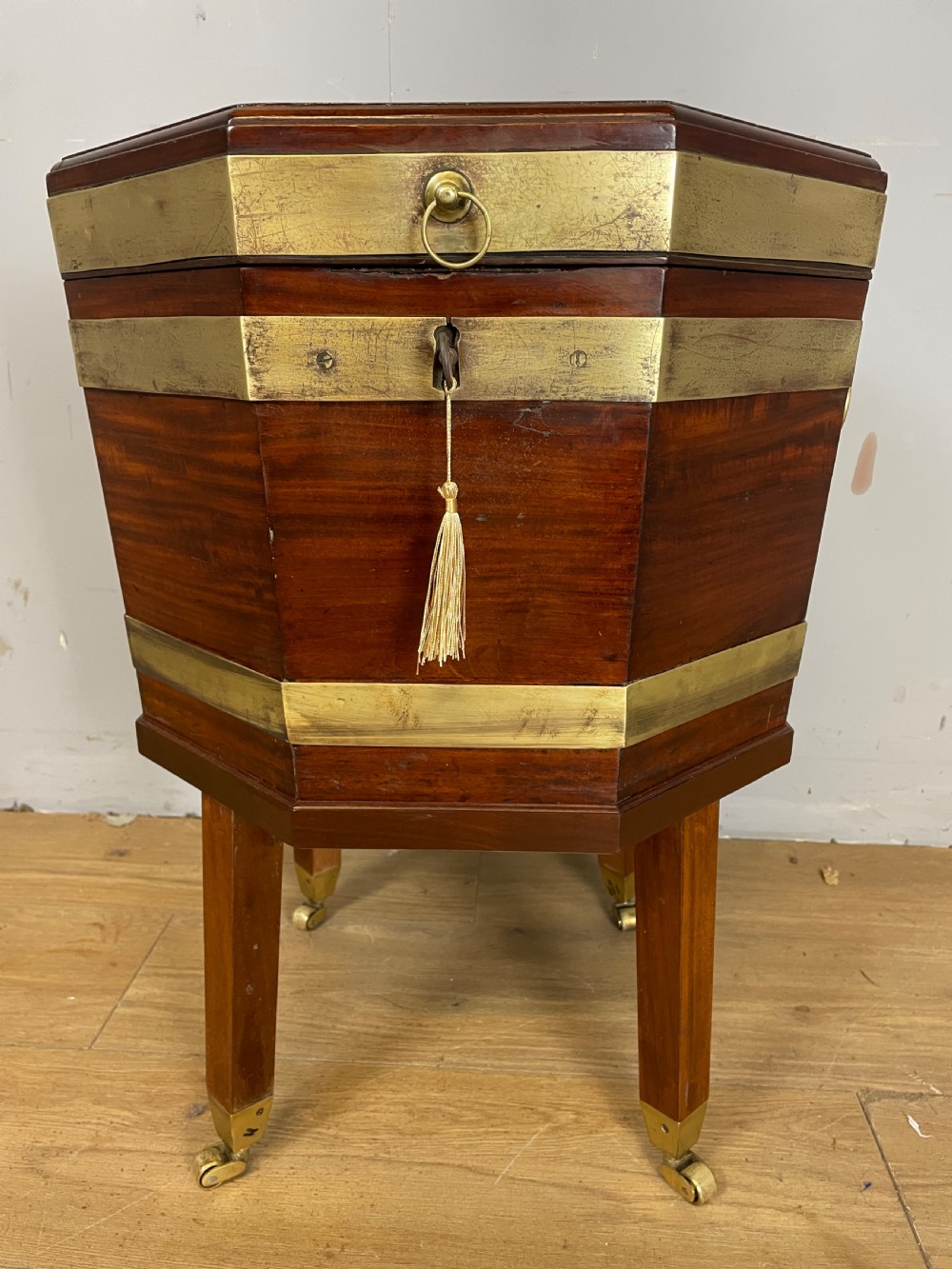 An octagonal Georgian mahogany cellarette bound with brass bands and supported by four square tapered legs on brass castors. View IV