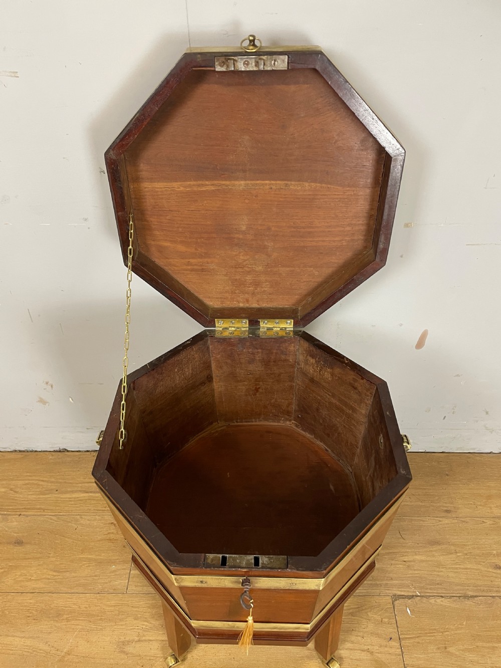 An octagonal Georgian mahogany cellarette bound with brass bands and supported by four square tapered legs on brass castors. View V