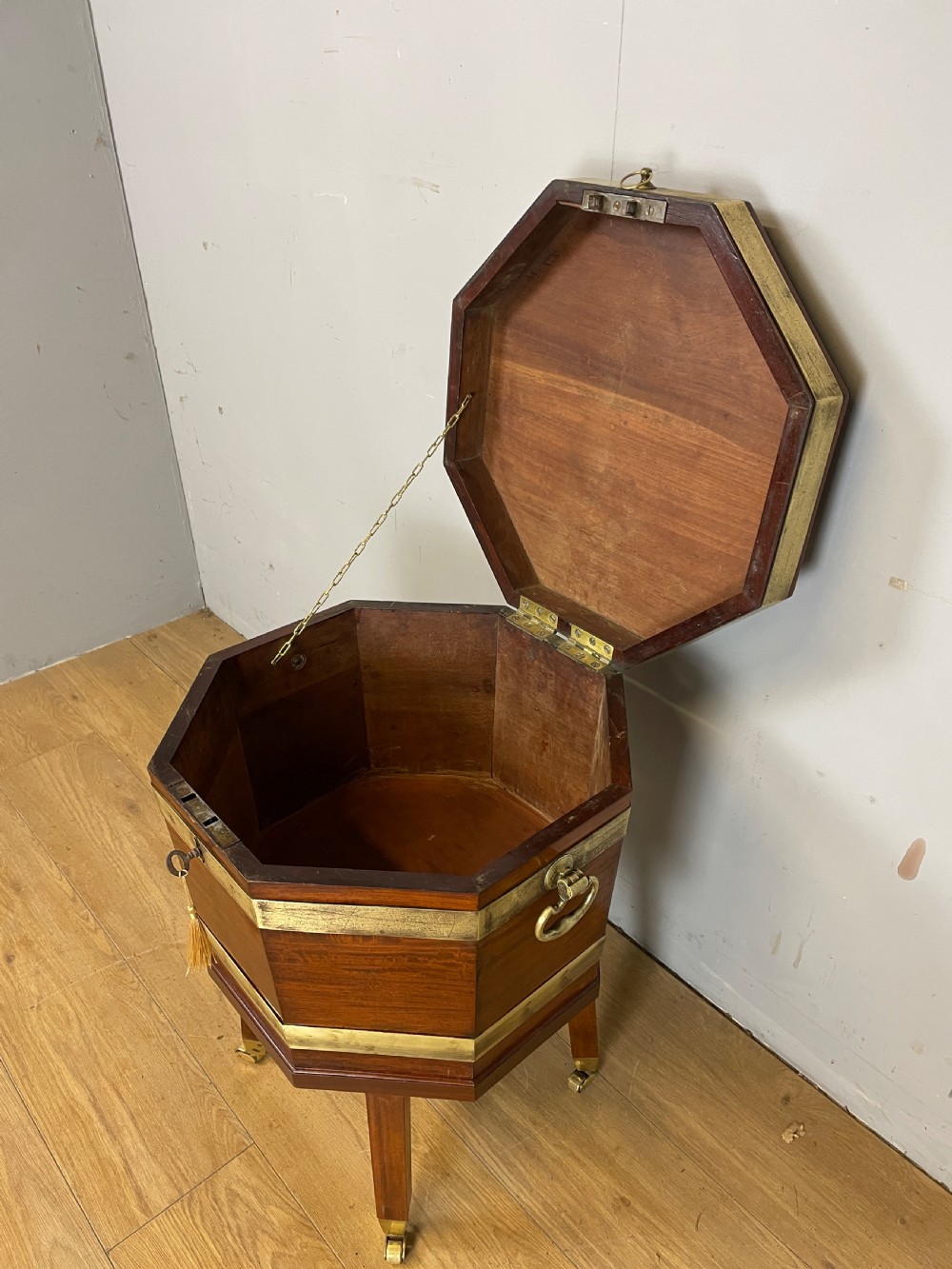 An octagonal Georgian mahogany cellarette bound with brass bands and supported by four square tapered legs on brass castors. View VII